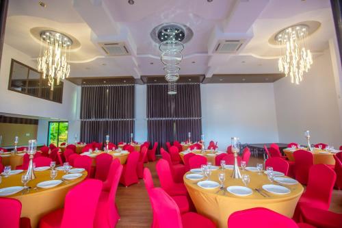 a room with pink tables and chairs and chandeliers at Horizon Hotel Romblon in Romblon
