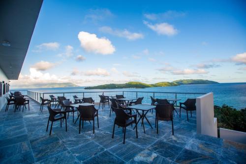 a restaurant with tables and chairs on a balcony overlooking the ocean at Horizon Hotel Romblon in Romblon