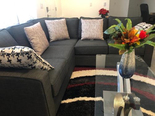 a living room with a gray couch and a vase with flowers at ChrisTon Exotic Suite - A Homey Suite in Halifax