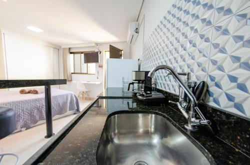 a kitchen with a sink and a room with a bed at Studios Cor Eucarístico PREMIUM in Belo Horizonte