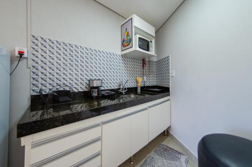 a small kitchen with a sink and a microwave at Studios Cor Eucarístico PREMIUM in Belo Horizonte