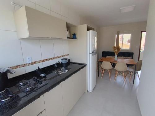 een keuken met een wastafel, een koelkast en een tafel bij Residencial Brisa do Mar 2 in Bombinhas