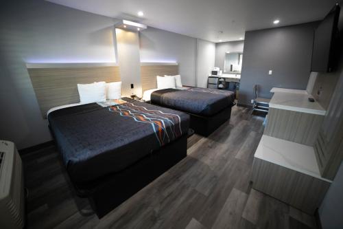 a hotel room with two beds and a desk at Travelodge by Wyndham Whittier in Whittier