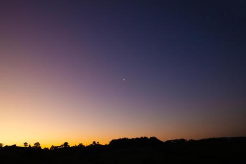 a sunset with the moon in the sky at Bever Farm in Waitoki