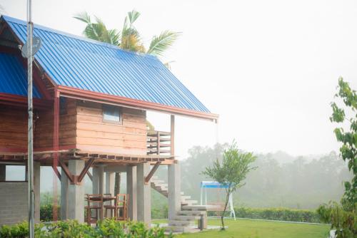 a house with a blue roof with a porch at Ceylon Nature Paradise in Uragasmanhandiya