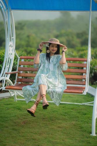 a young girl sitting on a bench wearing a hat at Ceylon Nature Paradise in Uragasmanhandiya