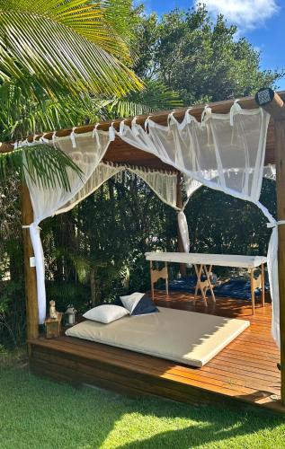 a bed on a wooden deck with a canopy at Costa do Sauipe Casa dentro do complexo hoteleiro in Costa do Sauipe