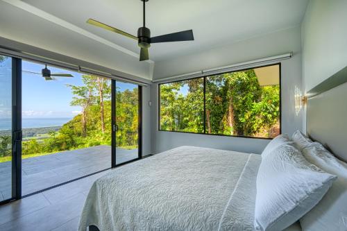 a bedroom with a bed and large glass windows at Brisas Del Mar Hills of Portalón Ocean View in Savegre