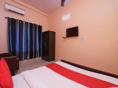 a bedroom with a bed and a tv on the wall at Hotel O Sunrise in Port Blair