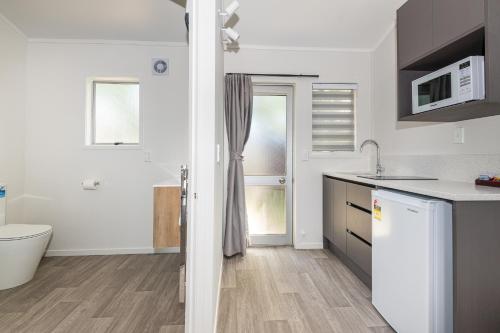 a white kitchen with a sink and a refrigerator at Aurora City Suites Motel in Rotorua