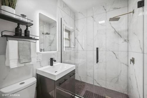 a white bathroom with a sink and a shower at The Chic Urban Oasis Near the Lake! in Chicago