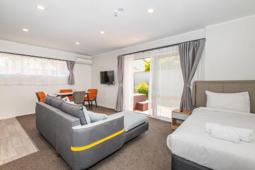 een slaapkamer met een bed, een bank en een tafel bij Aurora City Suites Motel in Rotorua