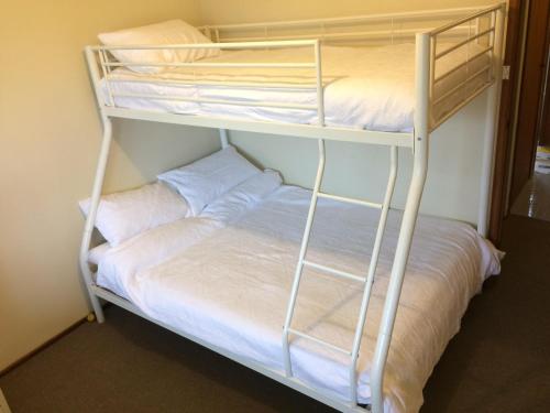 a bunk bed with white sheets and pillows on it at South Pacific in Scotts Head