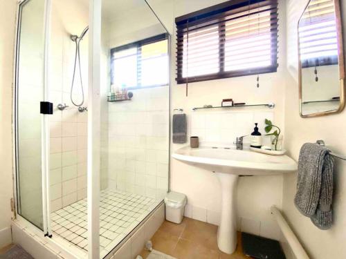 La salle de bains blanche est pourvue d'un lavabo et d'une douche. dans l'établissement Project Tranquility, Magnetic Island, à Nelly Bay