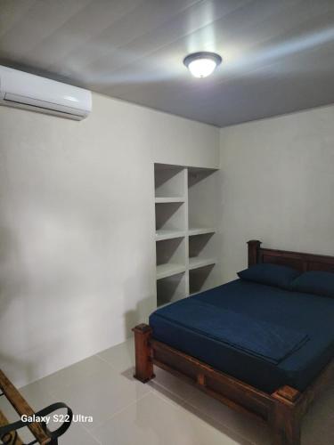 a bedroom with a blue bed and a shelf at Peluza's place in Puerto Jiménez