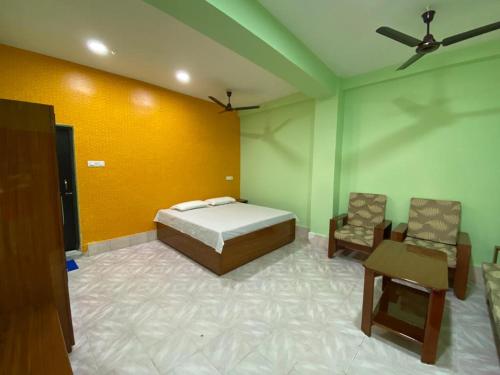 een slaapkamer met een bed en 2 stoelen. bij HOTEL RITZ in Guwahati