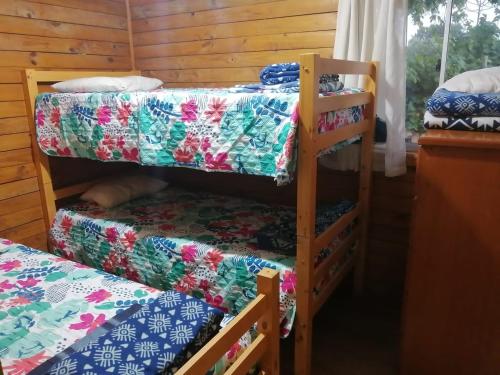 a room with two bunk beds and a table at Cabaña Bungalow SpA in Quillón