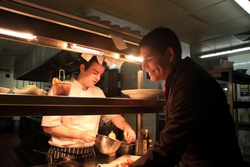 two men standing in a kitchen preparing food at Hazlewood Castle & Spa in Tadcaster