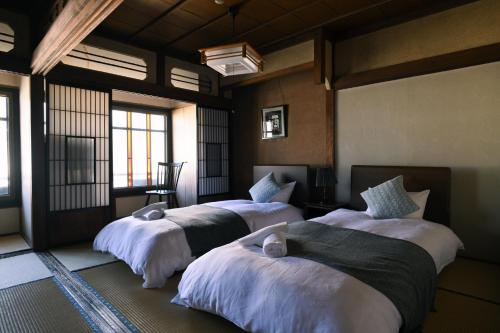 Nunoya Ryokan في ماتسوموتو: غرفة بثلاث اسرة في غرفة بها نوافذ