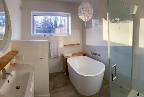 uma casa de banho com uma banheira e um chuveiro em vidro. em Le Camp Caché Shefford em Shefford