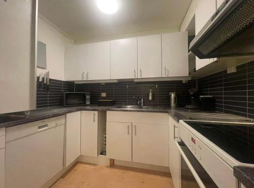 a kitchen with white cabinets and a sink at Cozy 2-Bed Apartment on the top of Tromsø! in Tromsø