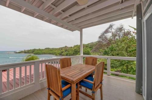 a table and chairs on a balcony with the ocean at Sir Sea Villas of Roatan LionFish 1 Bed 1 Bath in Roatán