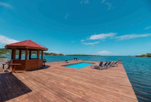a wooden dock with a gazebo and a swimming pool at Sir Sea Villas of Roatan LionFish 1 Bed 1 Bath in Roatán