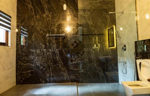 a bathroom with a shower with a black marble wall at Lush Acres in Thekkady