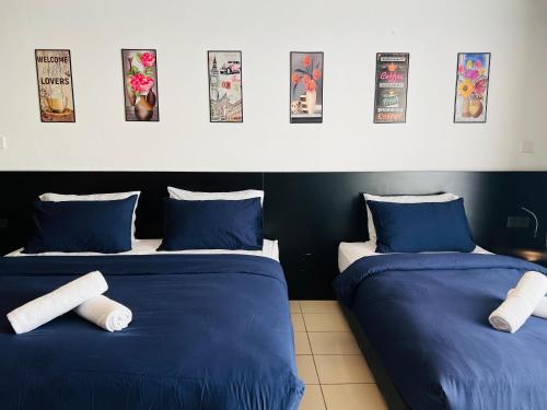 M Suite Homestay, Aeropod Sovo Kota Kinabalu في Tanjong Aru: سريرين في غرفة ذات أغطية زرقاء وبيضاء