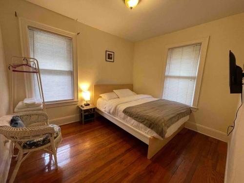 a bedroom with a bed and a chair and two windows at Entire Beautiful 1BR for You! [R] in Whitestone