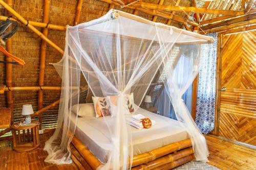 a bed in a room with a mosquito net at Tongo Hill Cottages in Moalboal