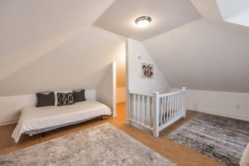 a white room with a bed and a staircase at Charming 3BR Century Home in Downtown Barrie in Barrie