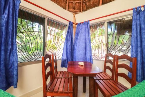 a table and chairs in a room with windows at Playa Lakin-ha beachfront cabins in Tulum