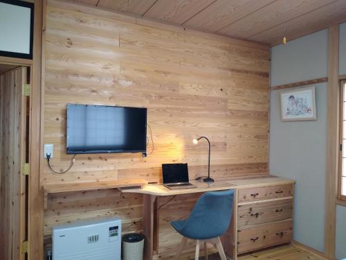 um quarto com uma secretária, um computador e um monitor em Robin's Lodge em Iiyama