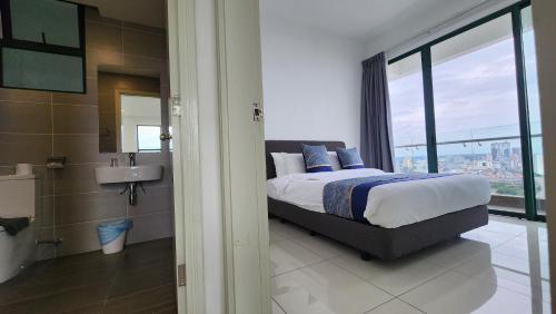 a bedroom with a bed and a bathroom with a window at The Suites SGR Melaka in Melaka