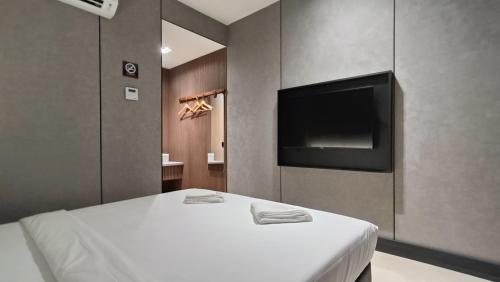 a bedroom with a bed and a flat screen tv at Urban Inn, Serai Wangi in Padang Serai