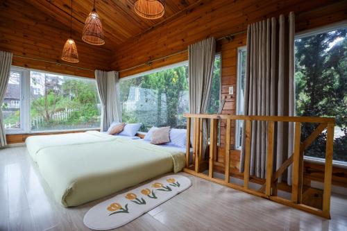 - une chambre avec un grand lit et de grandes fenêtres dans l'établissement Đom Đóm House Đà Lạt, à Đà Lạt