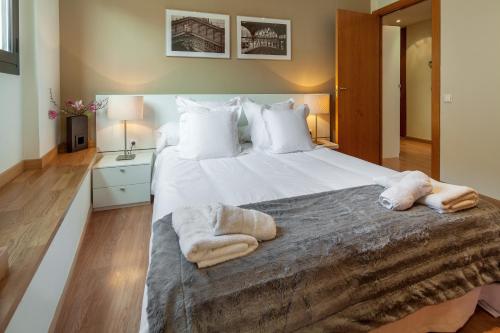 a bedroom with a large white bed with towels on it at Habitat Apartments Carders in Barcelona