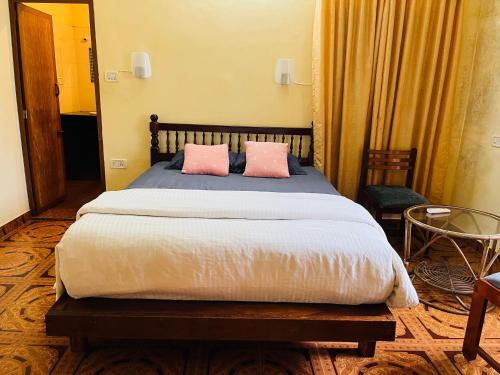 a bedroom with a bed with two pink pillows at Lavender residency in Varkala