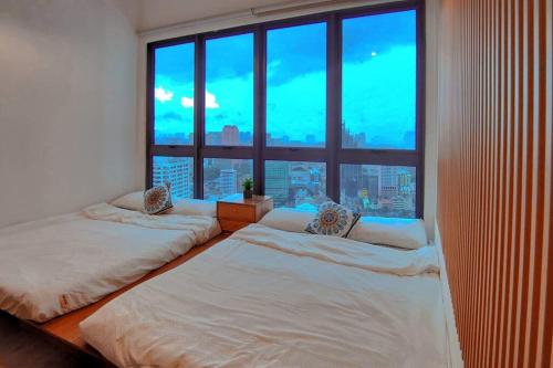 2 Betten in einem Zimmer mit einem großen Fenster in der Unterkunft Nordic Apartment, KLCC ZenSuites in Kuala Lumpur