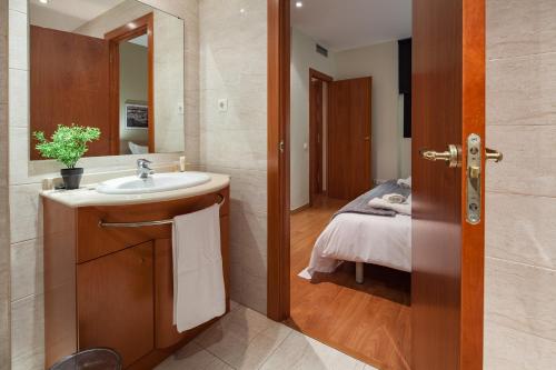Habitat Apartments Carders في برشلونة: حمام مع حوض وسرير