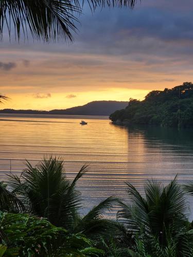 Un barco en el agua con una puesta de sol al fondo en casa vista linda, en Paraty