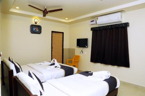 a hotel room with two beds and a ceiling fan at Hotel Elite Inn in Srikalahasti