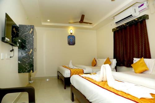 a hotel room with two beds and a window at Hotel Elite Inn in Srikalahasti