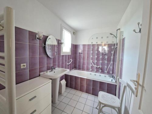 La salle de bains est pourvue de carrelage violet, d'un lavabo et d'une baignoire. dans l'établissement Holiday Home in Pordic near Sandy Beaches, à Pordic