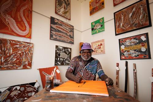 a man sitting at a table with a surfboard at Mercure Kakadu Crocodile in Jabiru