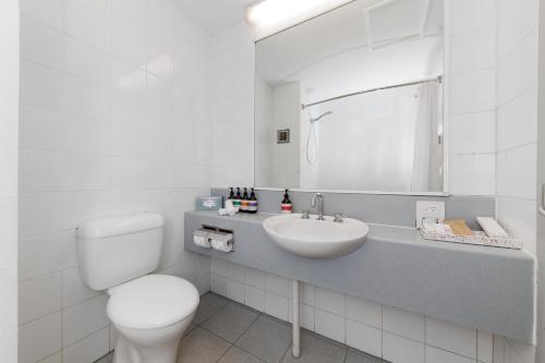 a white bathroom with a toilet and a sink at Mercure Kakadu Crocodile in Jabiru