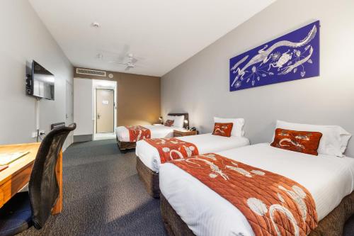 a hotel room with two beds and a desk at Mercure Kakadu Crocodile in Jabiru