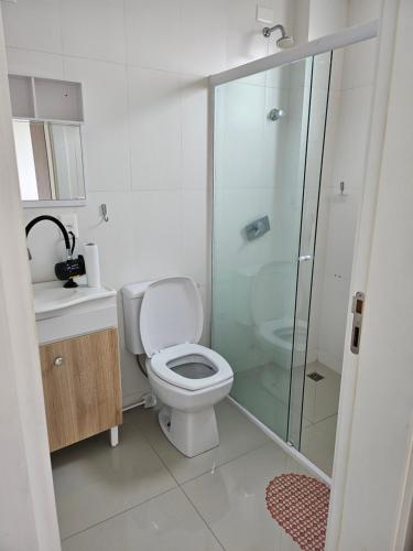 uma casa de banho com um WC e uma cabina de duche em vidro. em Apartamento 01 em Itapema