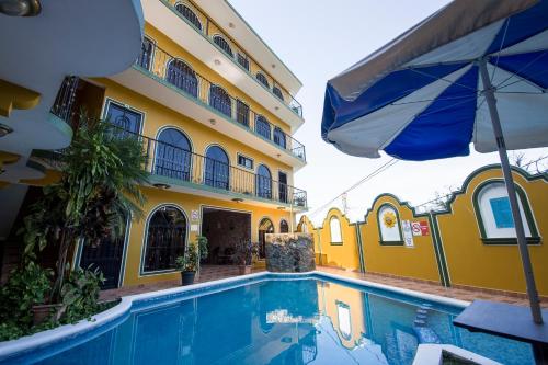 a hotel with a swimming pool and an umbrella at Hotel Dolores in Xilitla